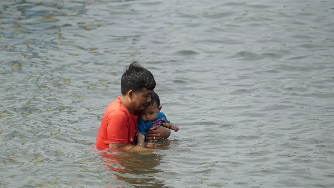 Orang tua yang sedang membawa anaknya berenang di Pantai Ancol. (Foto: Rizal Kris)