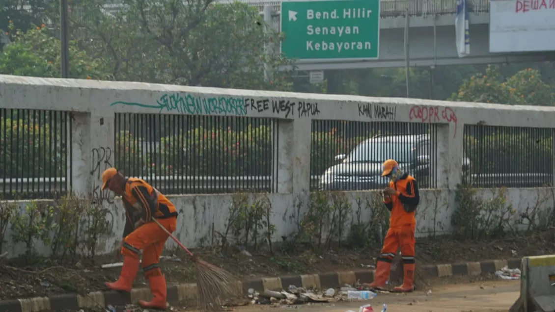 Pasukan orange membersihkan sampah dan puing-puing yang berada disekitaran depan gedung DPR.